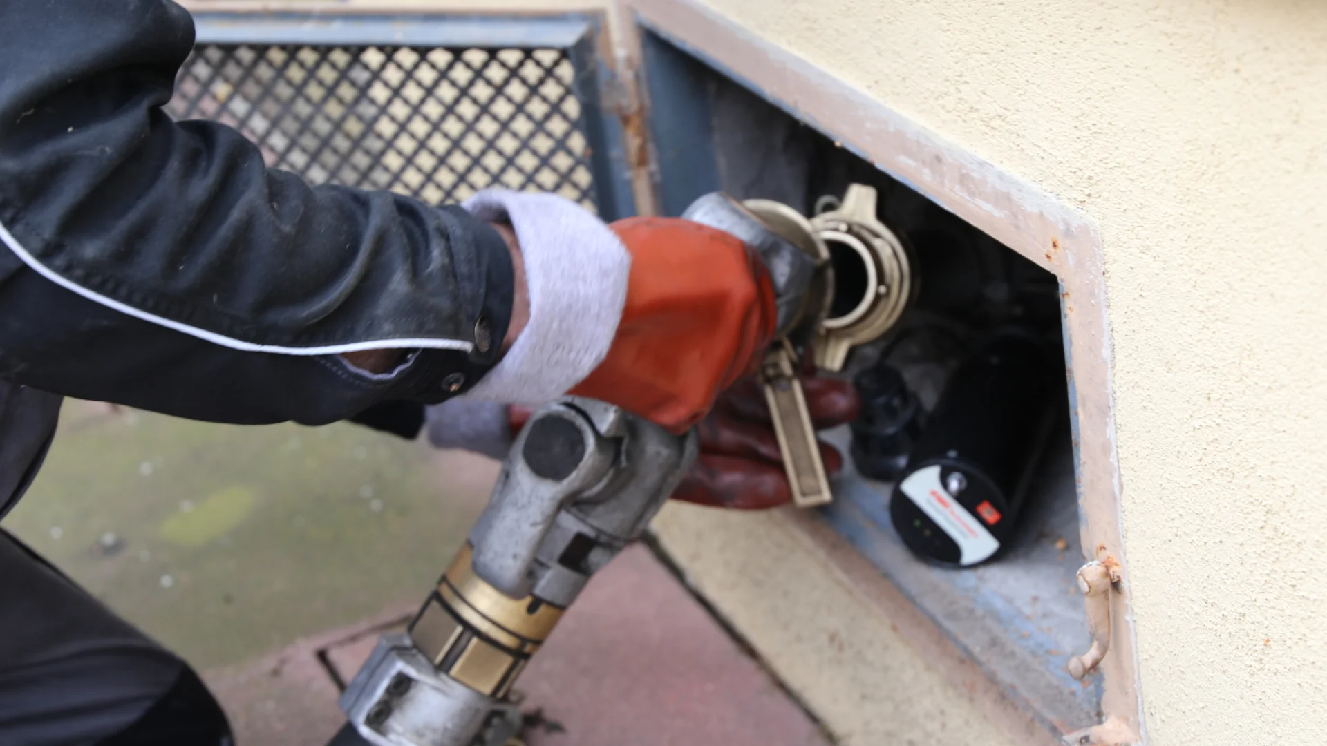 Photo of operator delivering oil to a home from a tanker hose