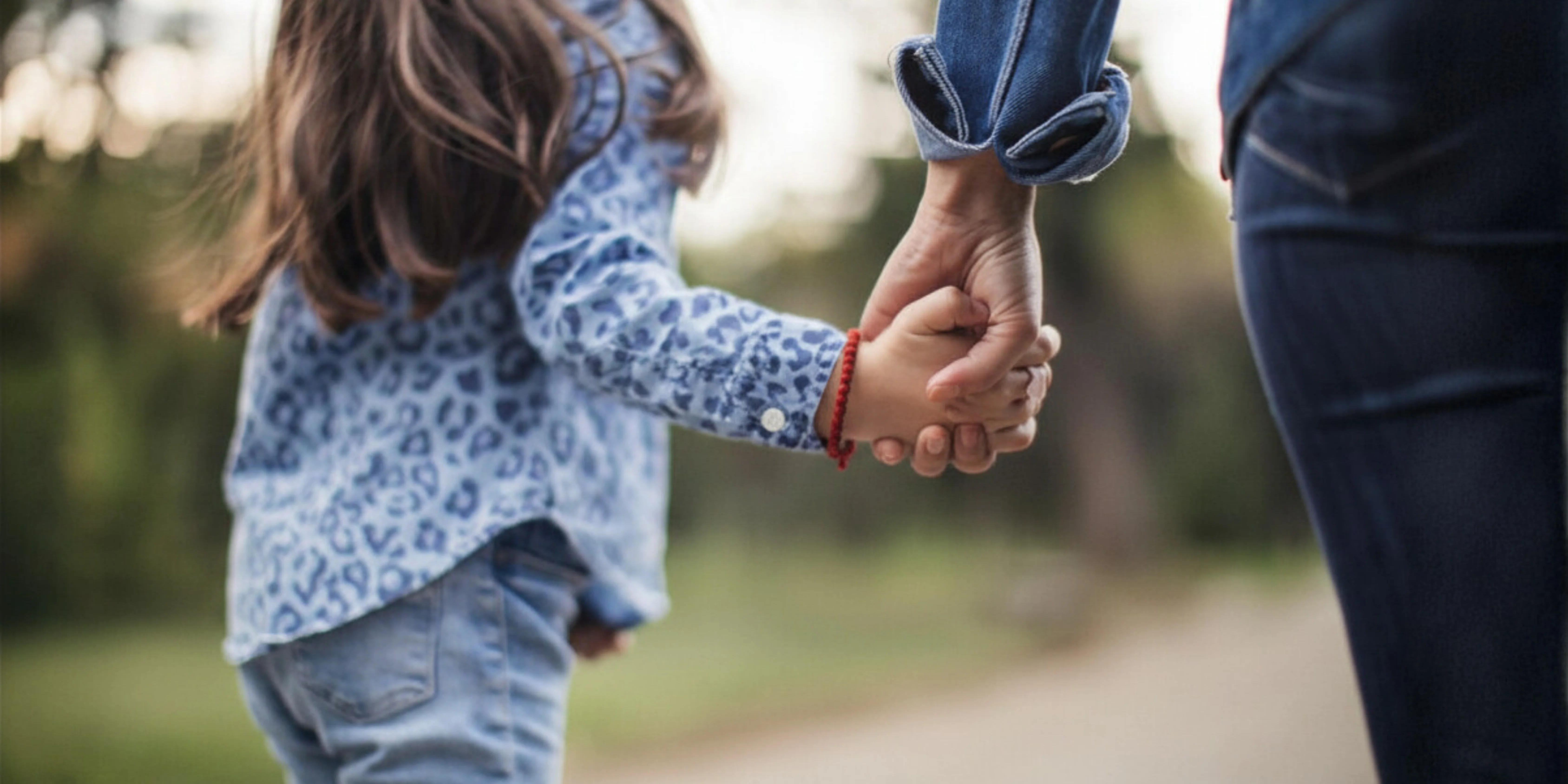 Child holding hands with adult