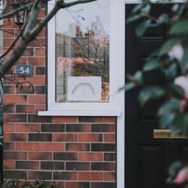 Photo of a modern house with a rainbow drawing in the window to illustrate a blog post about what COVID-19 has taught us about the benefit system